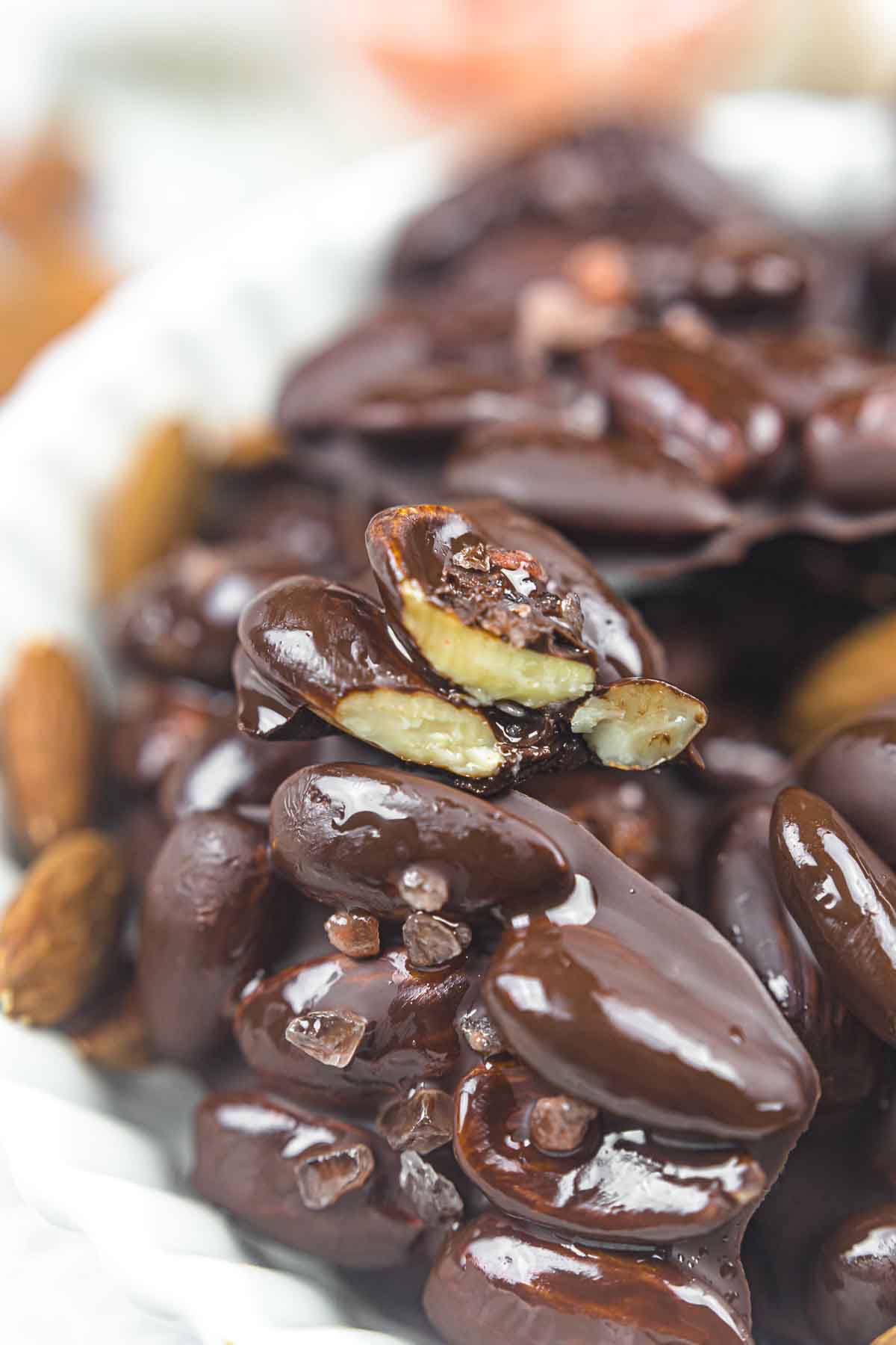 Chocolate covered almonds on a white plate.