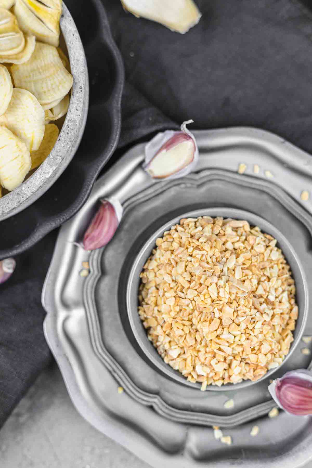A silver plate with garlic chips and a bowl of garlic.