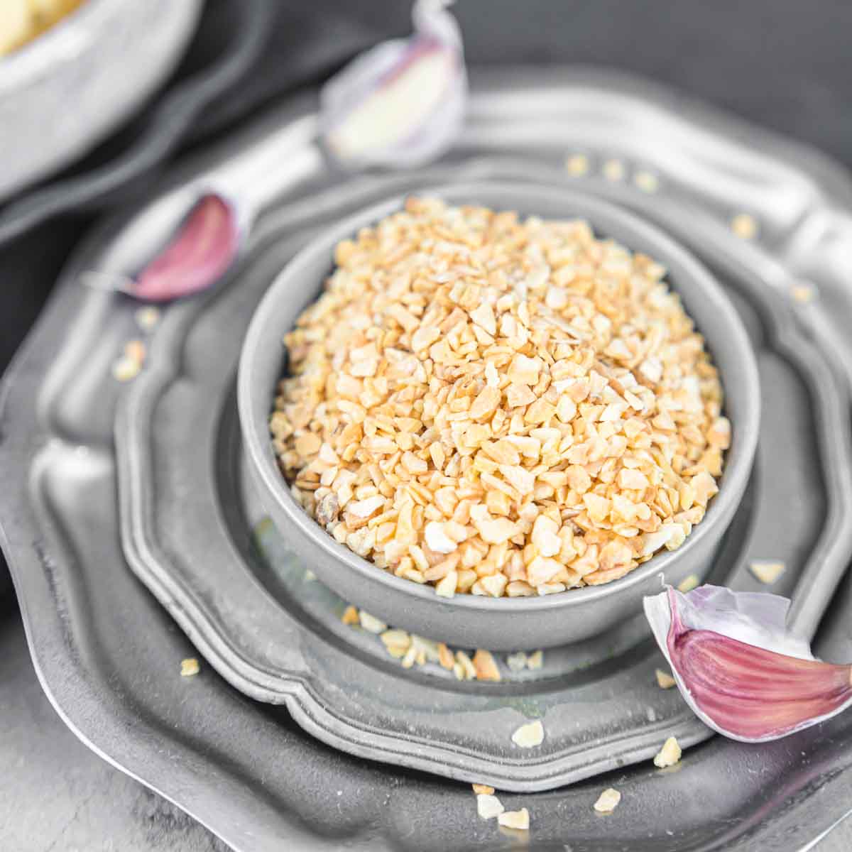 A bowl of granulated garlic on a silver plate.
