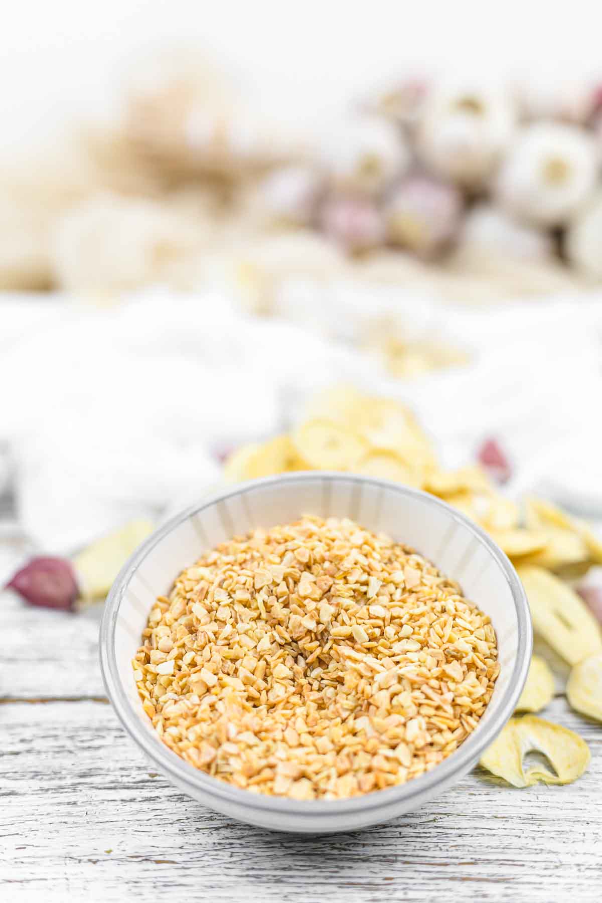 A bowl of granulated garlic on a wooden table.