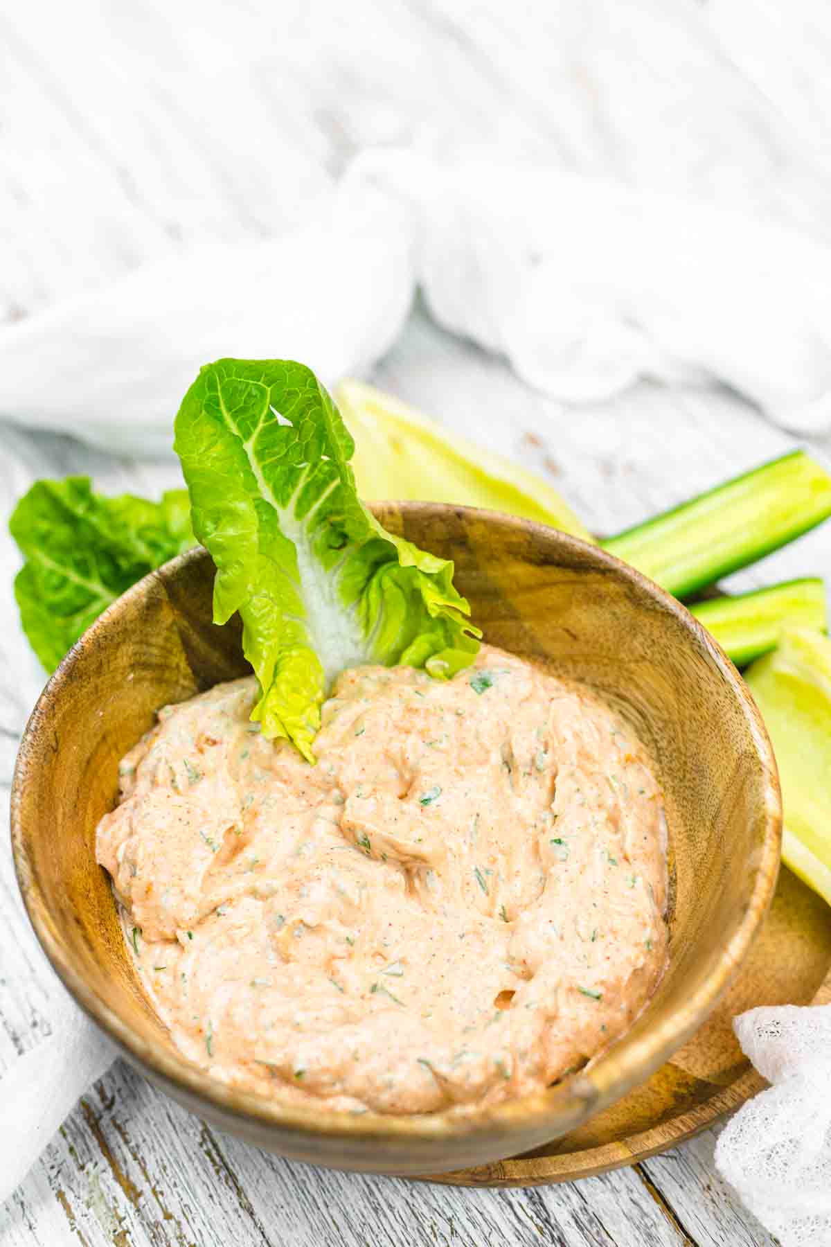 A bowl of creamy dip garnished with a leaf of lettuce.