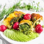 Grilled chicken with a spinach topping, served with sliced avocado and radishes.