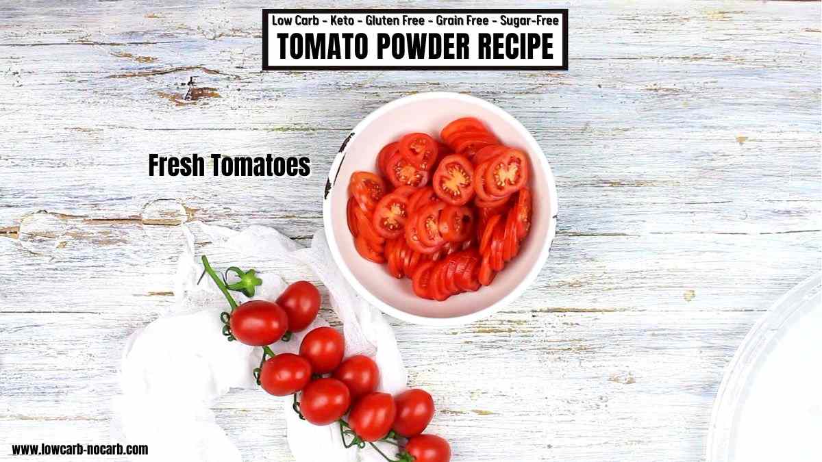 A bowl of sliced fresh tomatoes next to cherry tomatoes on a rustic wood surface, labeled as a recipe for tomato powder.