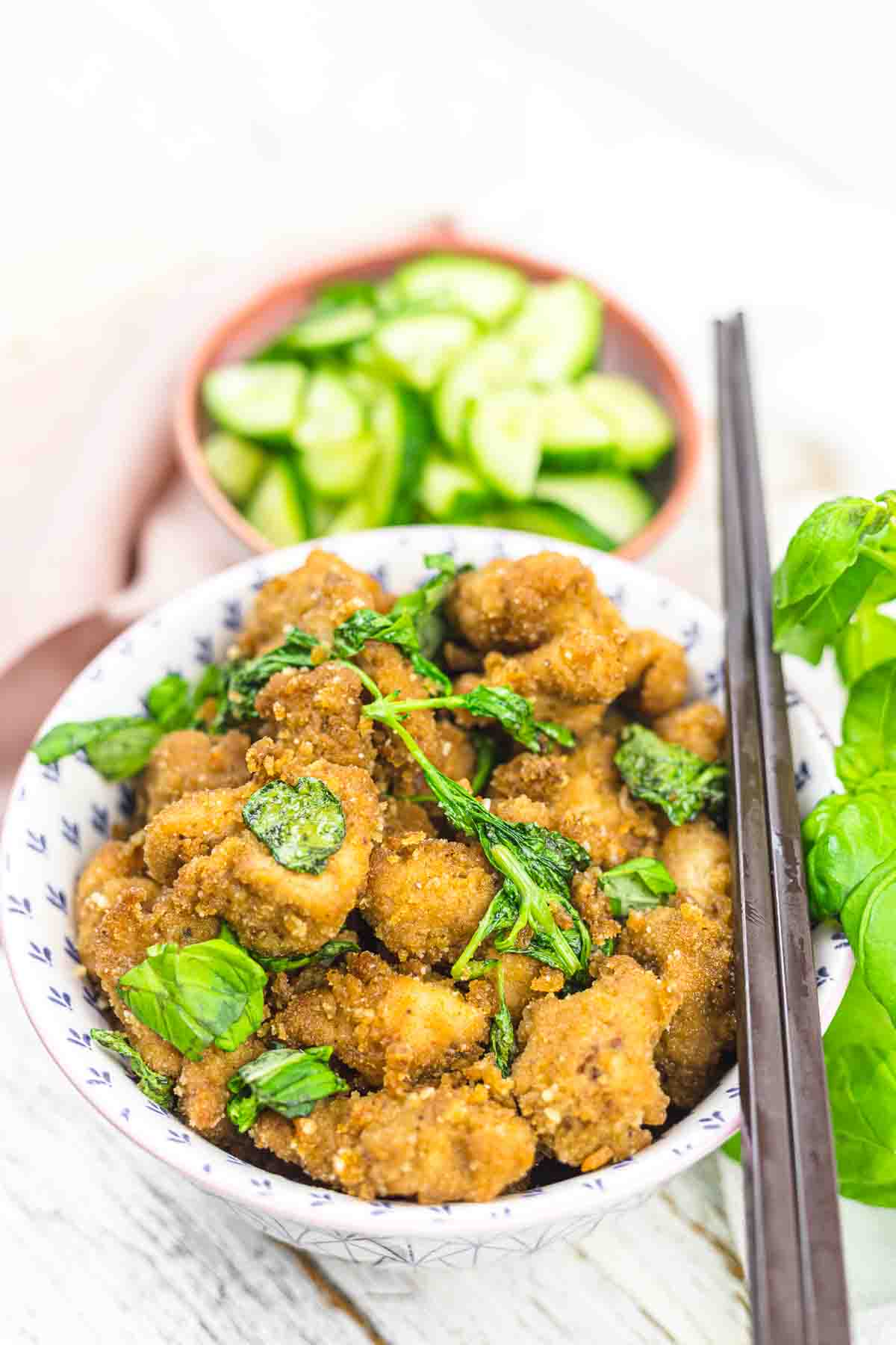 A bowl of crispy fried chicken with basil.