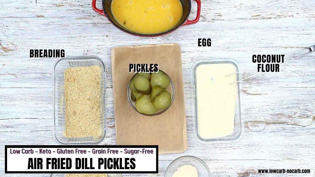Ingredients for air fried dill pickles are laid out on a table: breading, pickles, egg, and coconut flour, each in separate bowls, labeled for a low carb recipe.