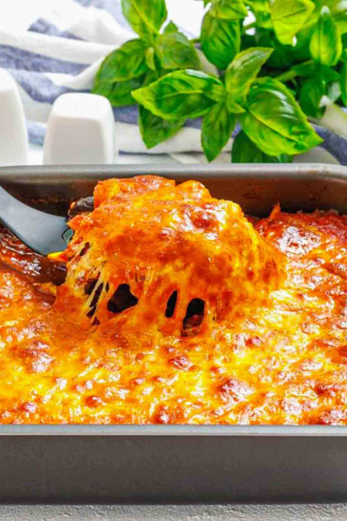 Cheesy casserole scoop lifted from baking pan.