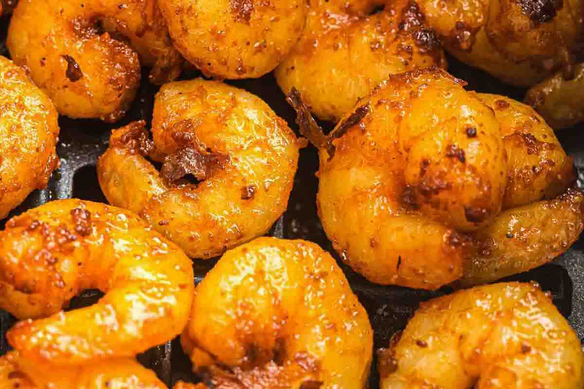 Close-up of several cooked shrimp coated in a golden, seasoned spice mix.