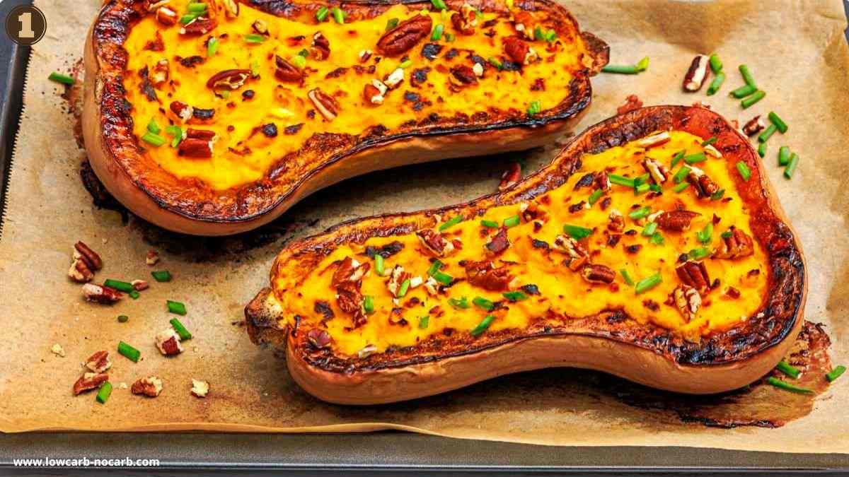 Two roasted butternut squash halves on parchment paper, filled with mashed flesh, topped with chopped pecans and chives.
