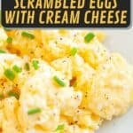 A close-up of scrambled eggs mixed with cream cheese, garnished with chopped chives and black pepper on a white plate.