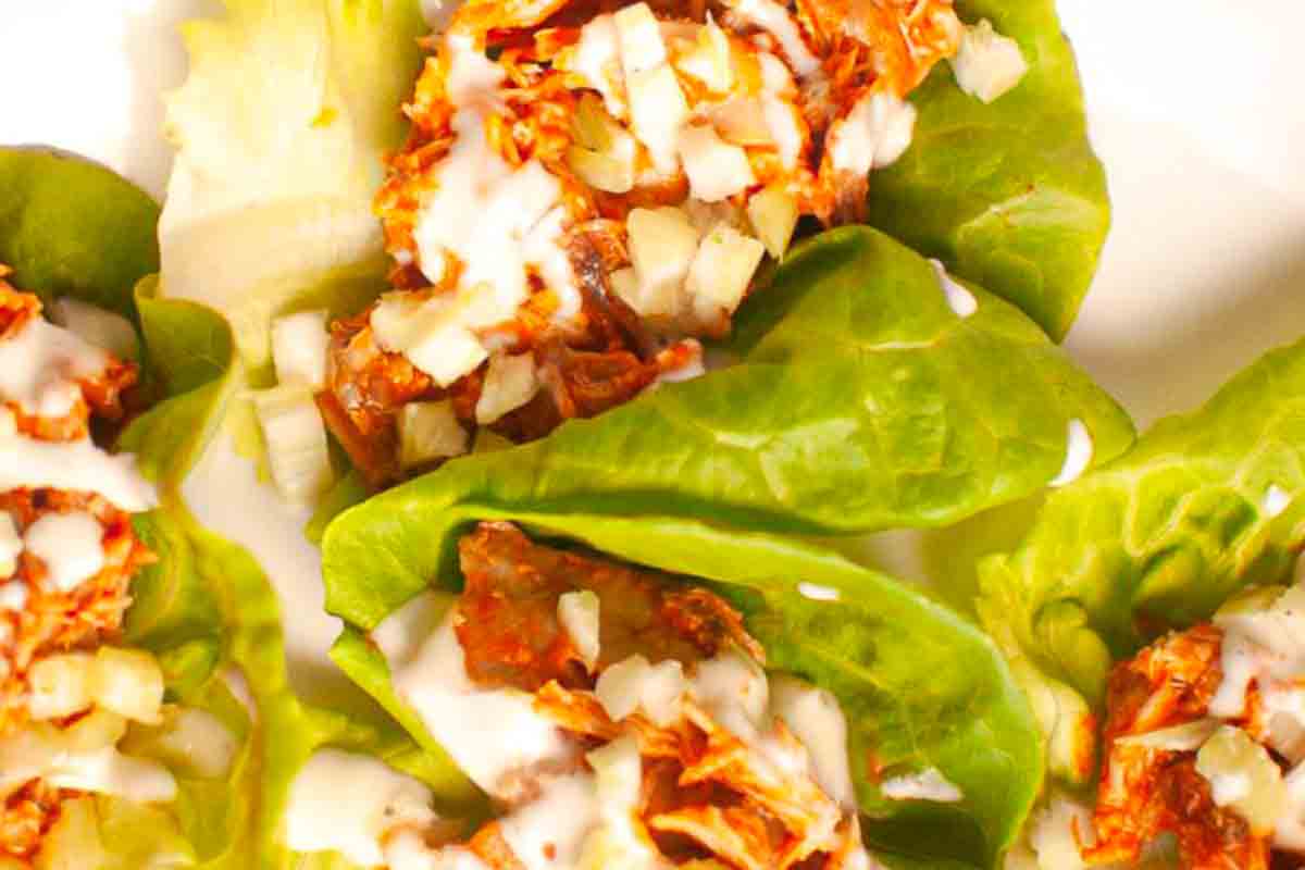 Shredded chicken with diced onions and creamy sauce served in fresh green lettuce leaves.