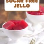 Two white bowls filled with red, cubed sugar-free Jello are placed on a white surface with a gold spoon beside one bowl. Text on the image reads "Easy to Make Sugar Free Jello.