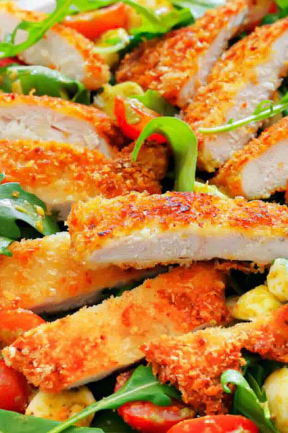 Crispy breaded chicken slices served on a bed of mixed greens, cherry tomatoes, and other salad ingredients.