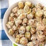 A bowl filled with breaded and fried okra pieces, dusted with a light coating of seasoning.