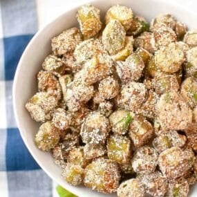 A bowl filled with breaded and fried okra pieces, dusted with a light coating of seasoning.