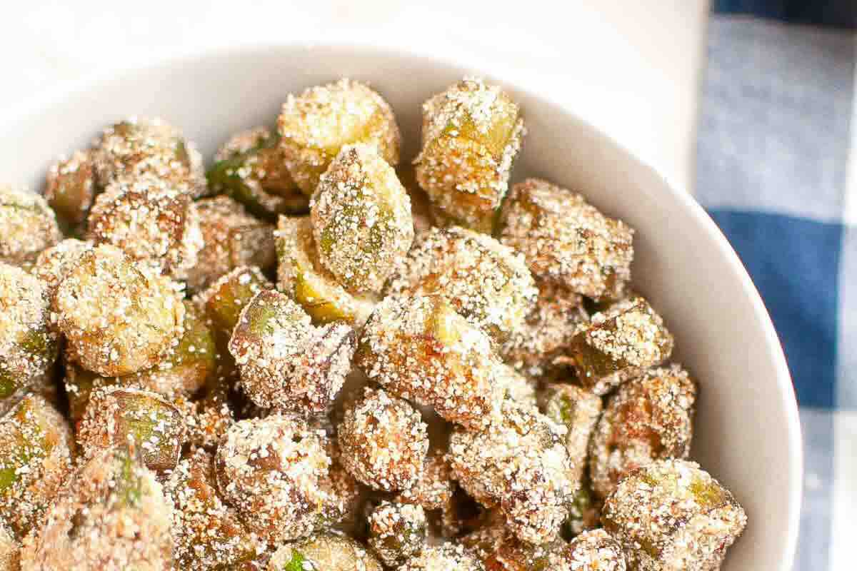 A bowl filled with breaded, seasoned fried okra pieces, viewed from above.