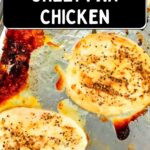 Three seasoned chicken breasts baked on a sheet pan, with browned edges and juices visible on the metal pan.