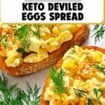 Two slices of bread topped with keto deviled egg spread and garnished with fresh dill, surrounded by extra dill on a white surface.