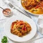Plate of chicken cooked with red and green bell peppers in a savory sauce.